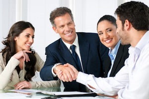 stock-photo-mature-businessman-shaking-hands-to-seal-a-deal-with-his-partner-and-colleagues-in-a-modern-office-70139677